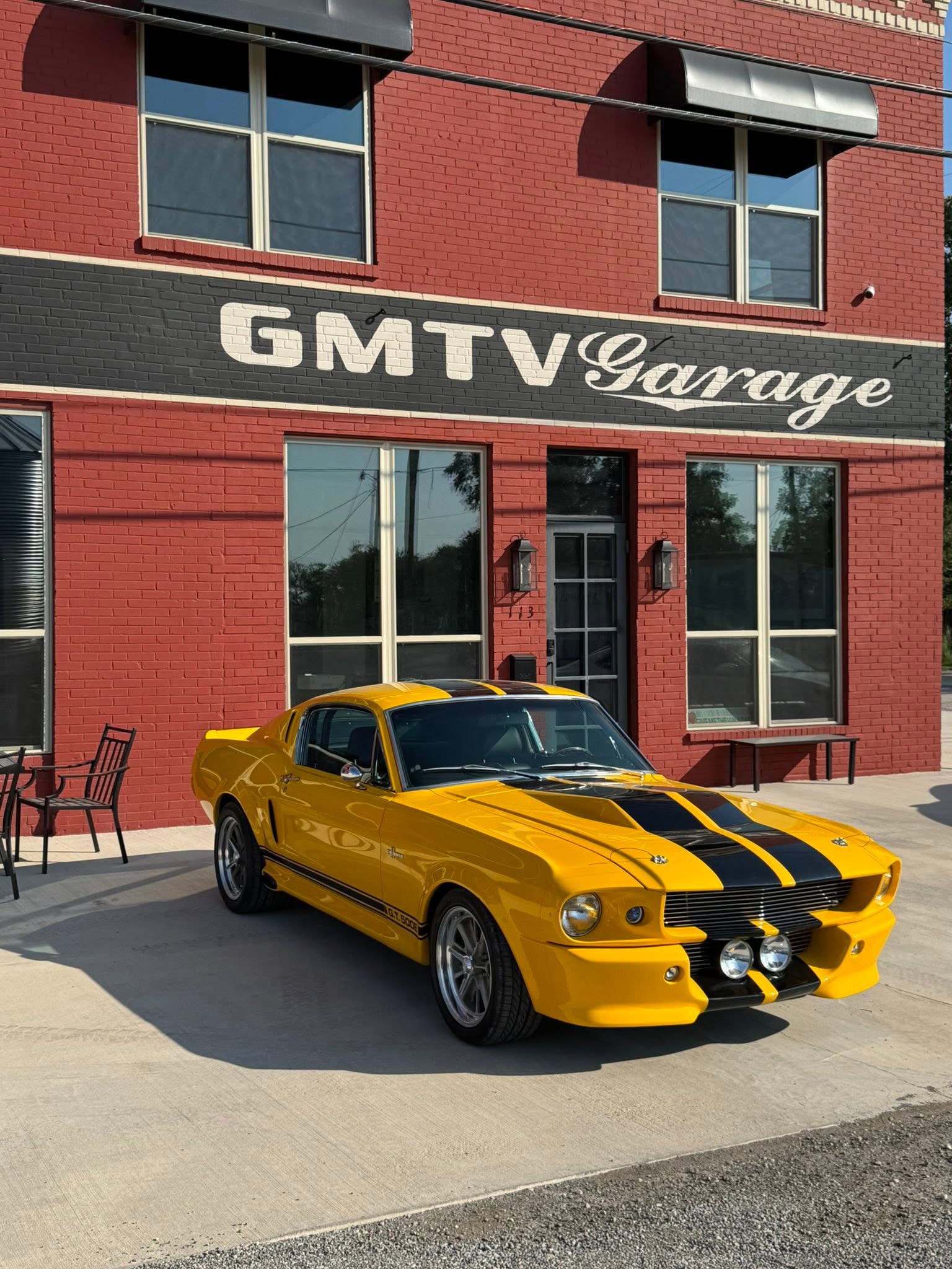 Yellow striped Mustang outside the red GMTV Garage building